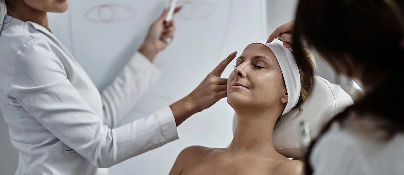 Operatrice in camice esegue un trattamento viso su una cliente in cabina