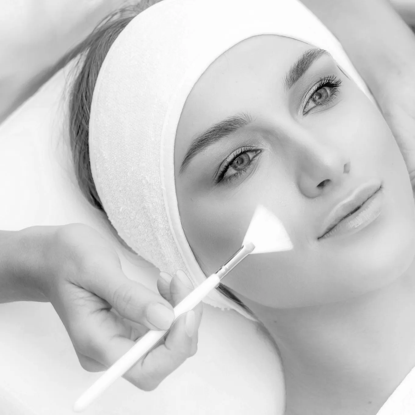 Operatrice applica una maschera viso con il pennello durante un trattamento